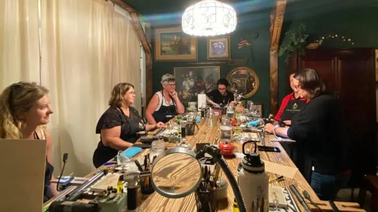 a group of people gather around a table to learn the art of ring making