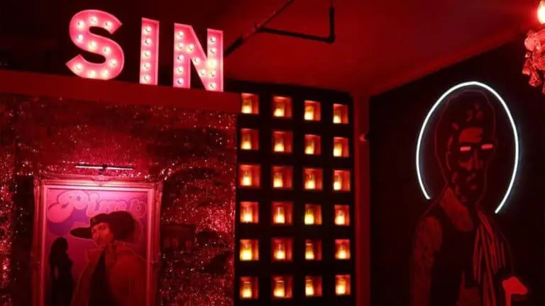 a large "sin" sign up in the corner of bar. It's dimly lit.