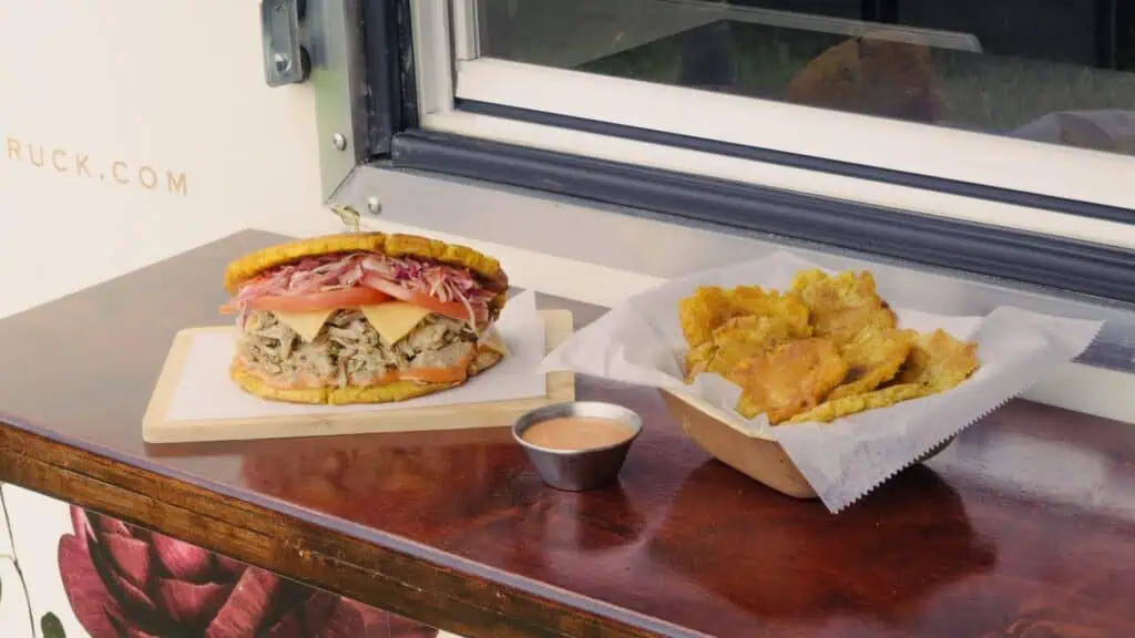 tostones in a basket and a sandwich on a board