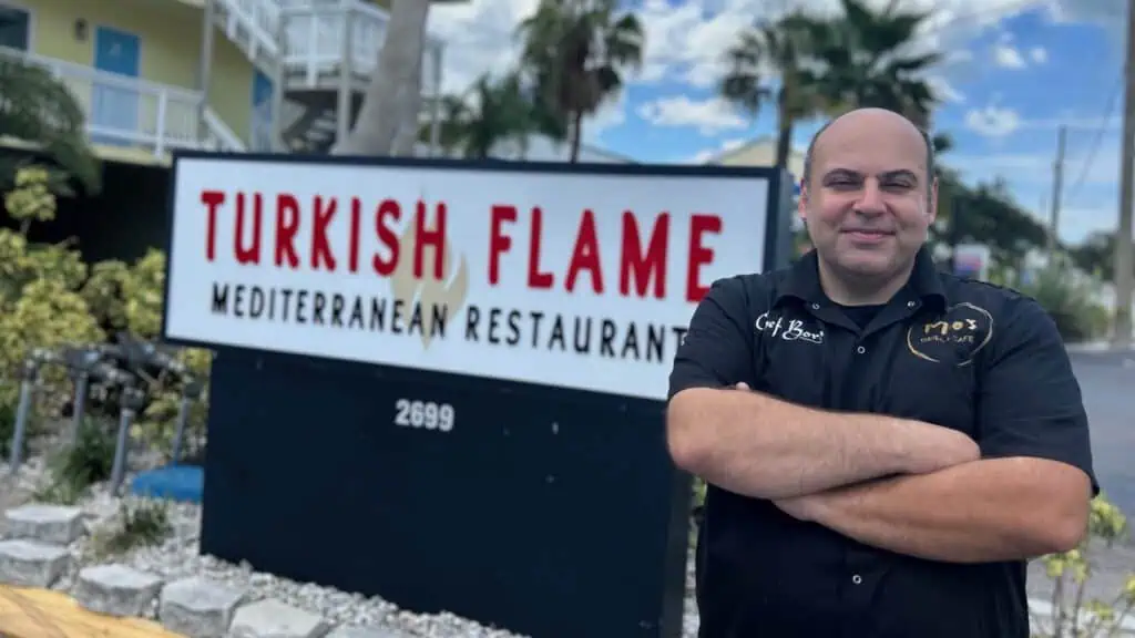 man standing in front of sign with arms crossed