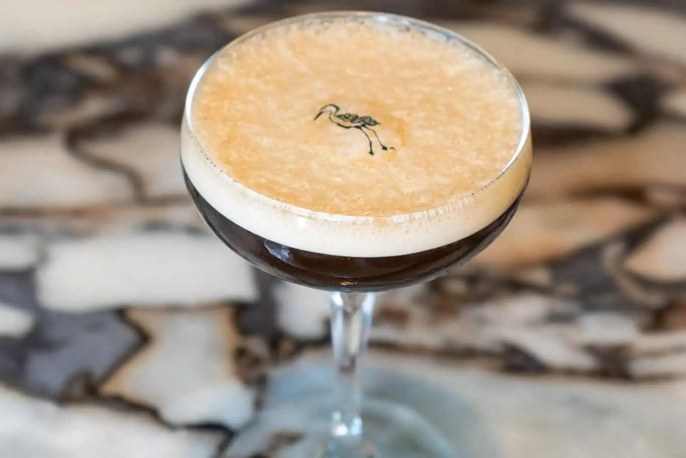 An espresso martini has a tiny image of a shorebird stamped into the foam.