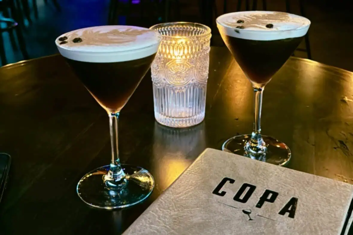 Two espresso martinis sit on a table next to a candle and a menu labeled "COPA."