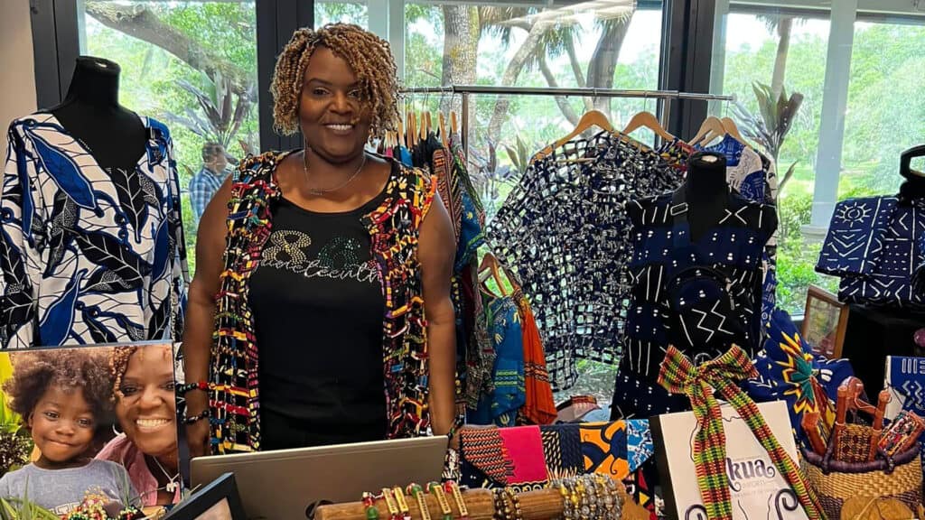 a woman poses in front of a stand at a local market