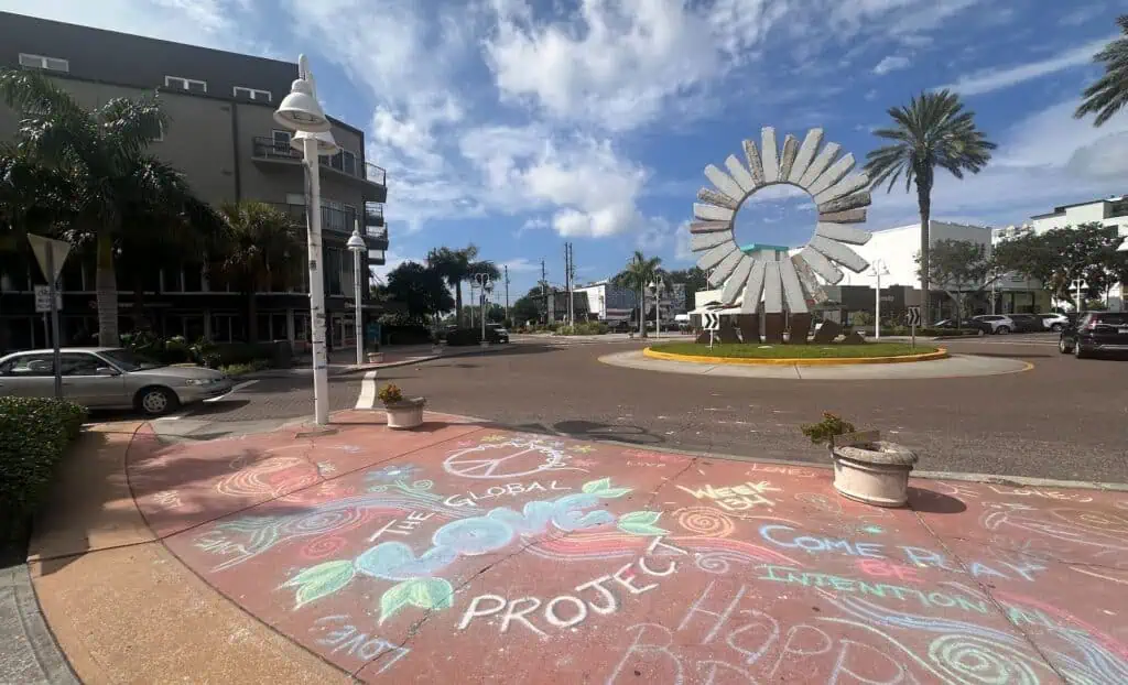 chalk art on a sidewalk. a large sculpture is visible in the background 