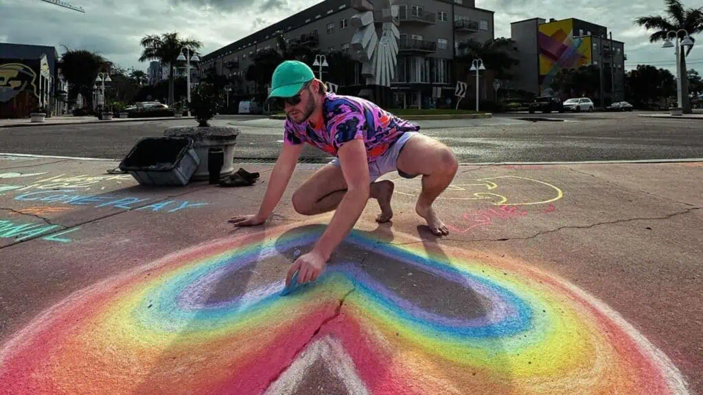 Man chalking colorful heart on sidewalk