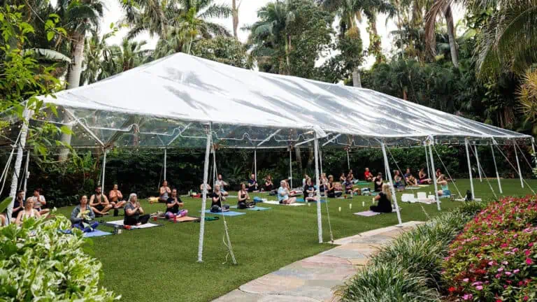 a group of people practice yoga under a tent