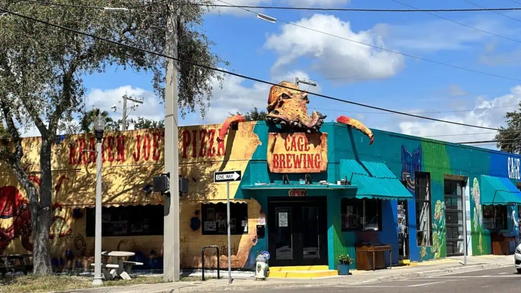 exterior of a brewery with a colorful mural out front and an octopus statue on top