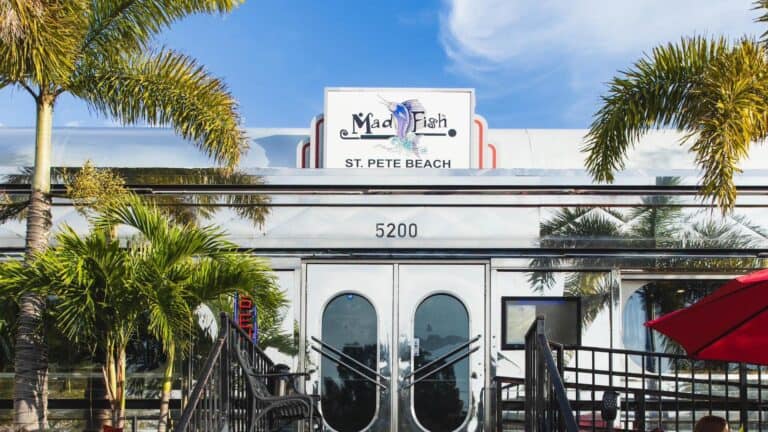 exterior of a restaurant with palm trees around the front door