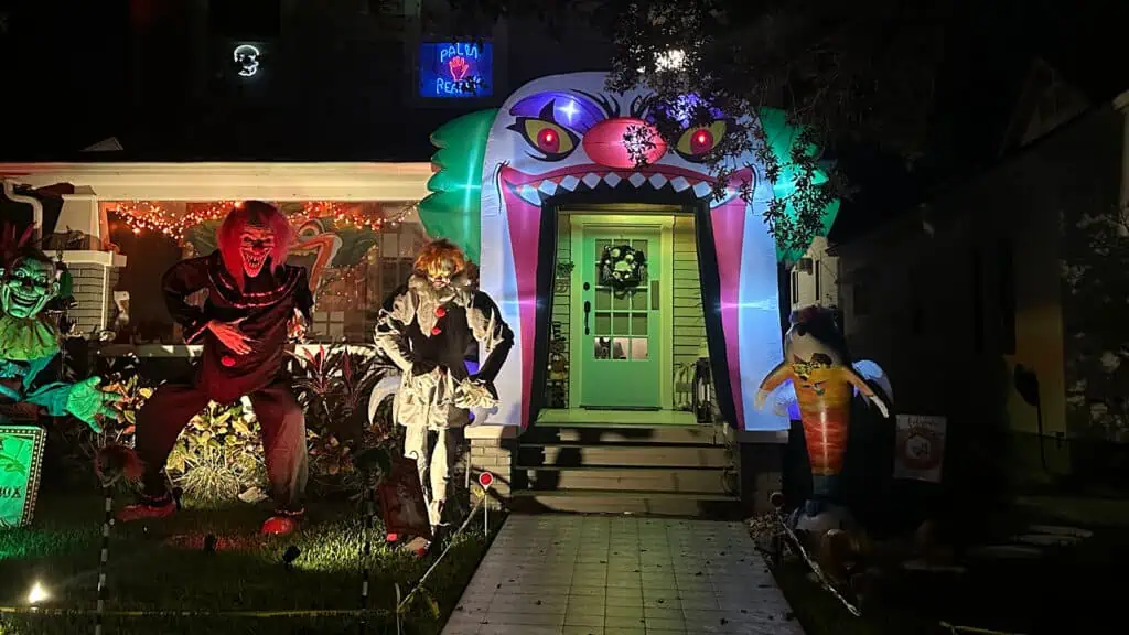 multiple clowns outside a home with a carnival entrance at the front door