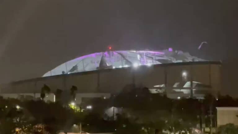 a tarp roof flies off of a baseball stadium