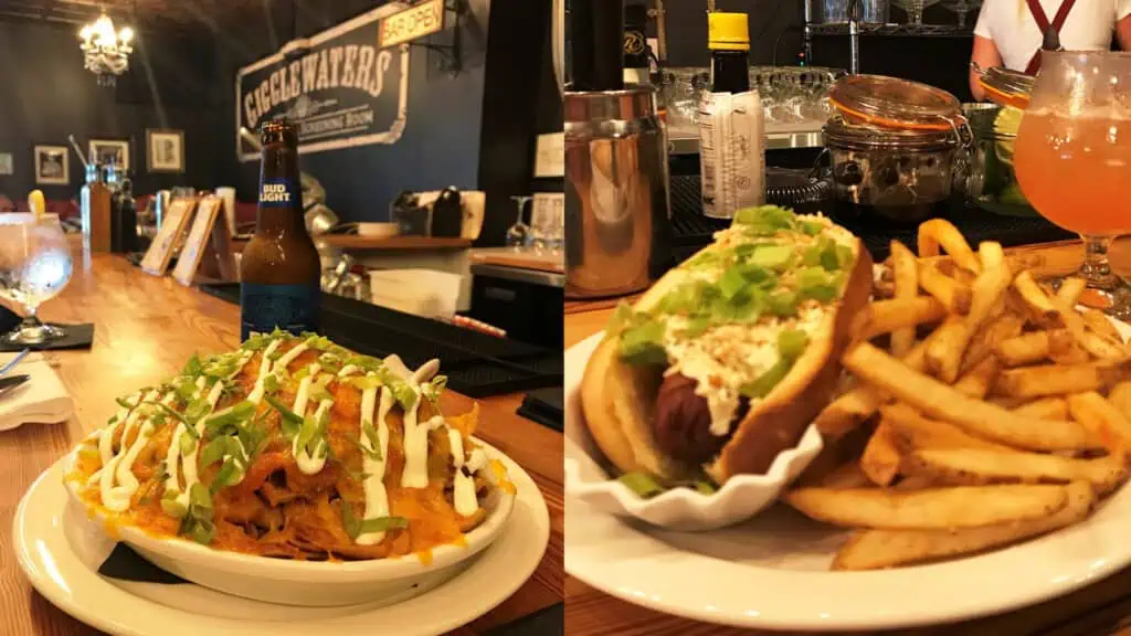 hot dog on plate beside frito pie on plate in dim bar.