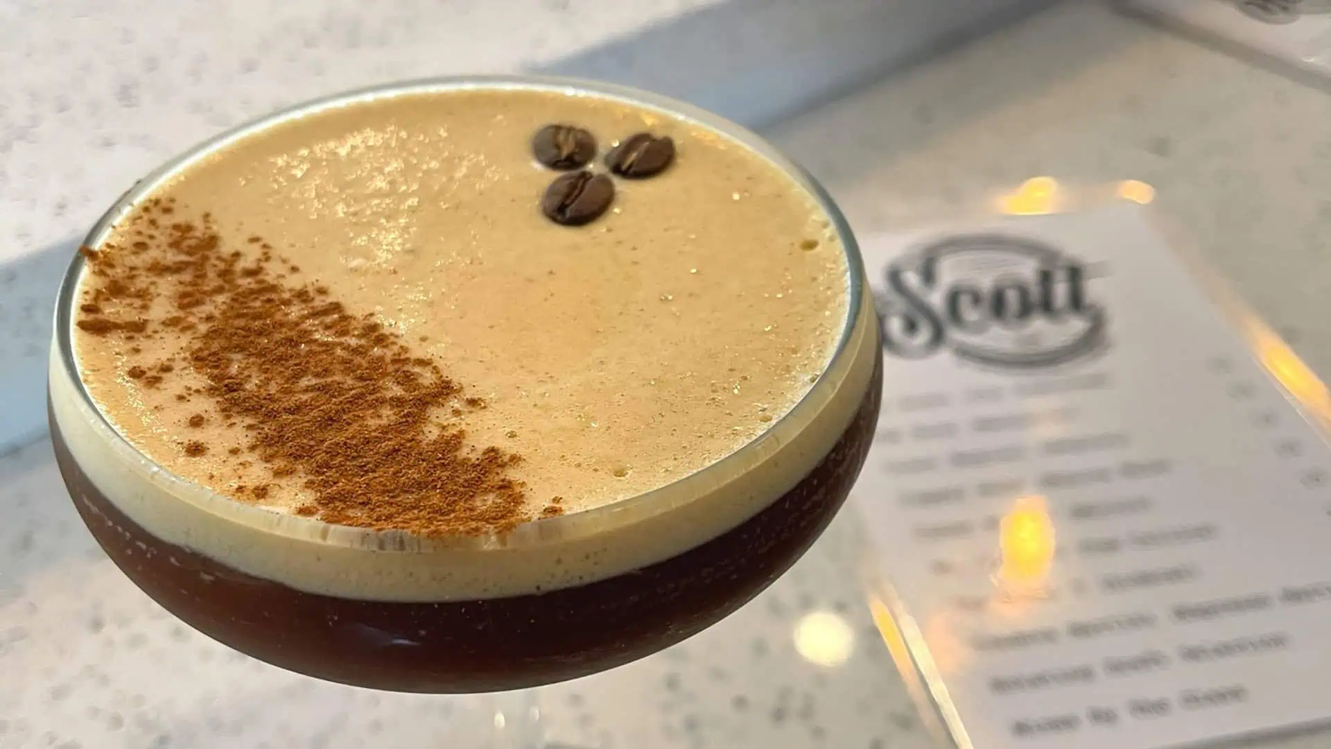 espresso martini on countertop with three espresso beans visible in the drink