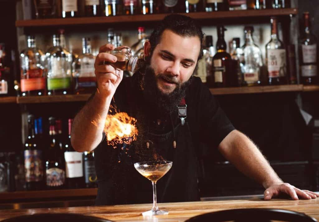 man mixing cocktail behind bar.