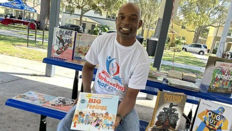 a man poses with a book in a park