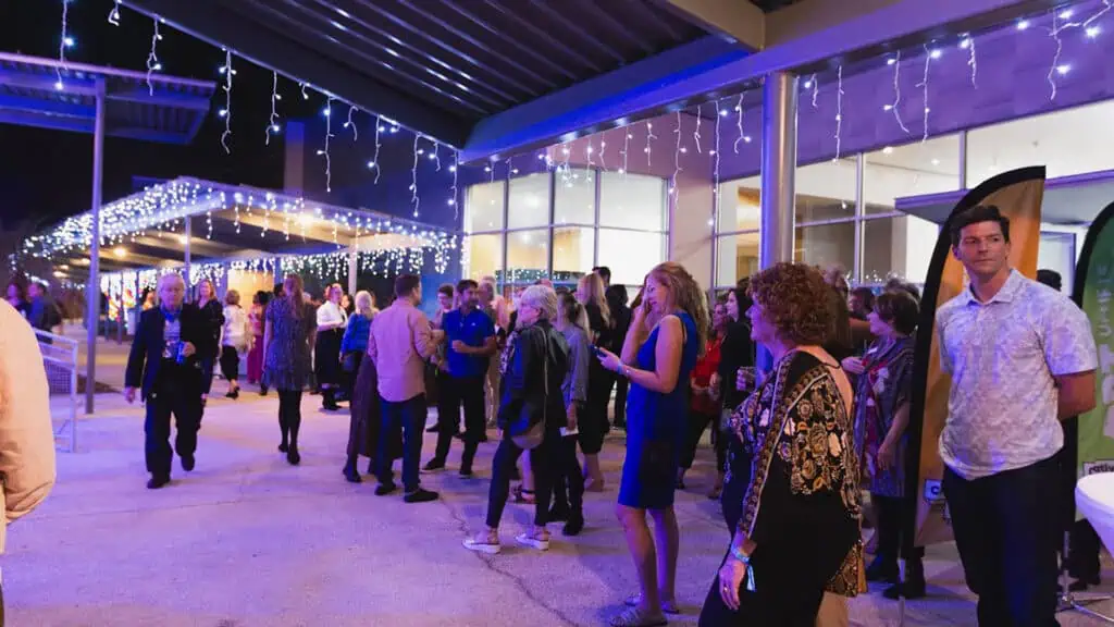 people stand under purple lights at an outdoor arts performance