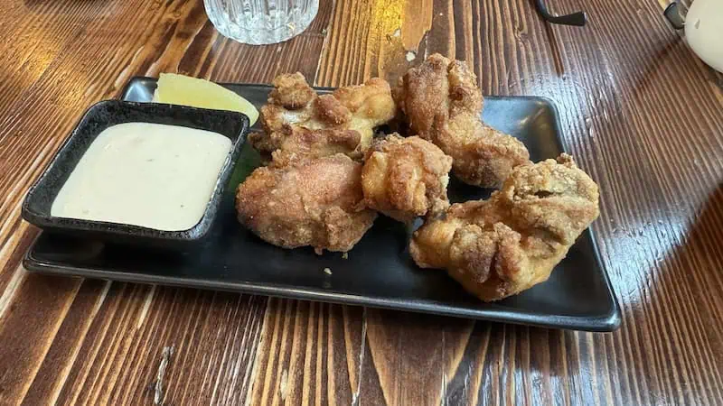 Karaage at Hakata Ramen Bar. Fried chicken pieces on a black dish with dipping sauce and lemon wedge.