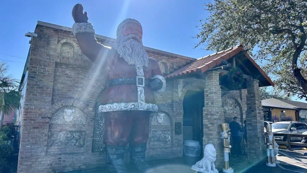 exterior of a market and deli with a mega-sized Santa statue to the left for the front door