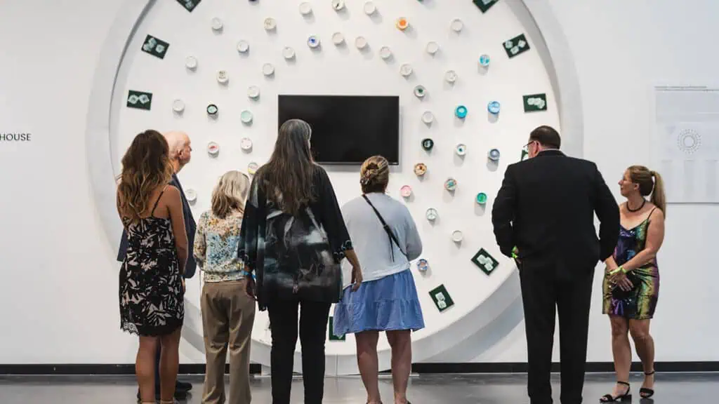 people in an art gallery observing a large scale work 