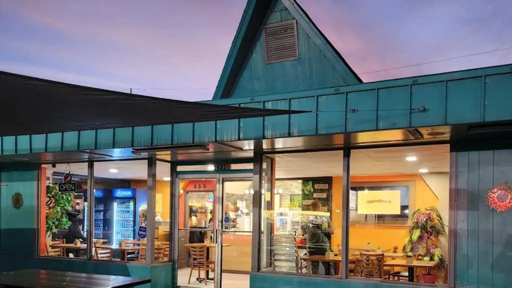 Exterior of a restaurant with a blue paint job and a pointed roof 