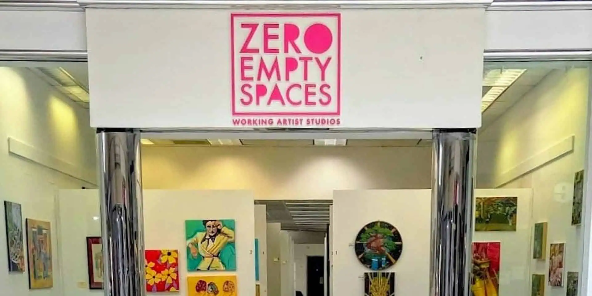 The entrance to "Zero Empty Spaces," a working artist studio with a bright pink sign and walls adorned with vibrant artwork