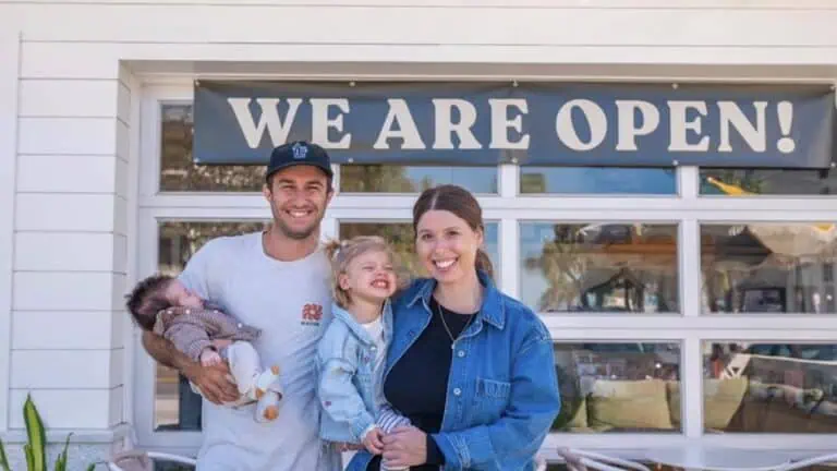 a group of people pose in front of a coffee shop