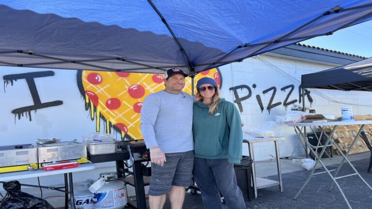 two people standing under blue tent