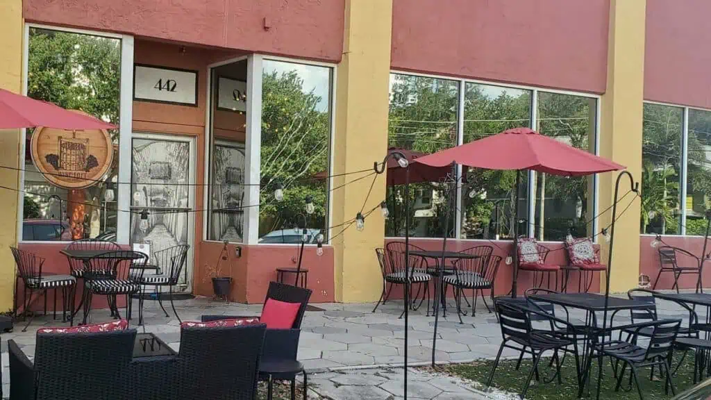 exterior of the building with tables, chairs, and umbrellas outside.