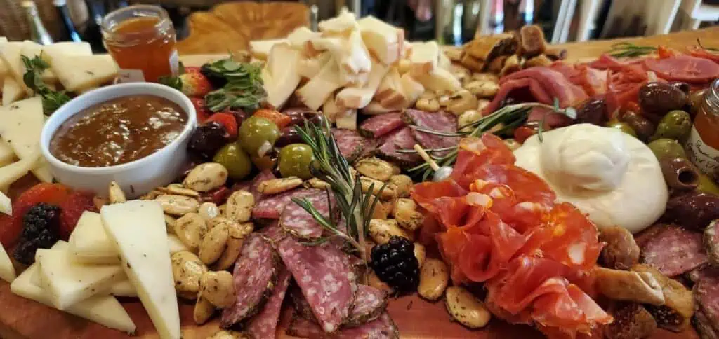 A vibrant charcuterie board featuring a variety of cured meats, cheeses, olives, nuts, fresh fruits, and spreads arranged beautifully on a wooden platter.