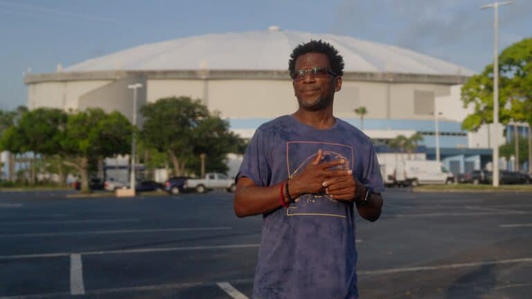 a man stands in front of a large stadium with a closed dome