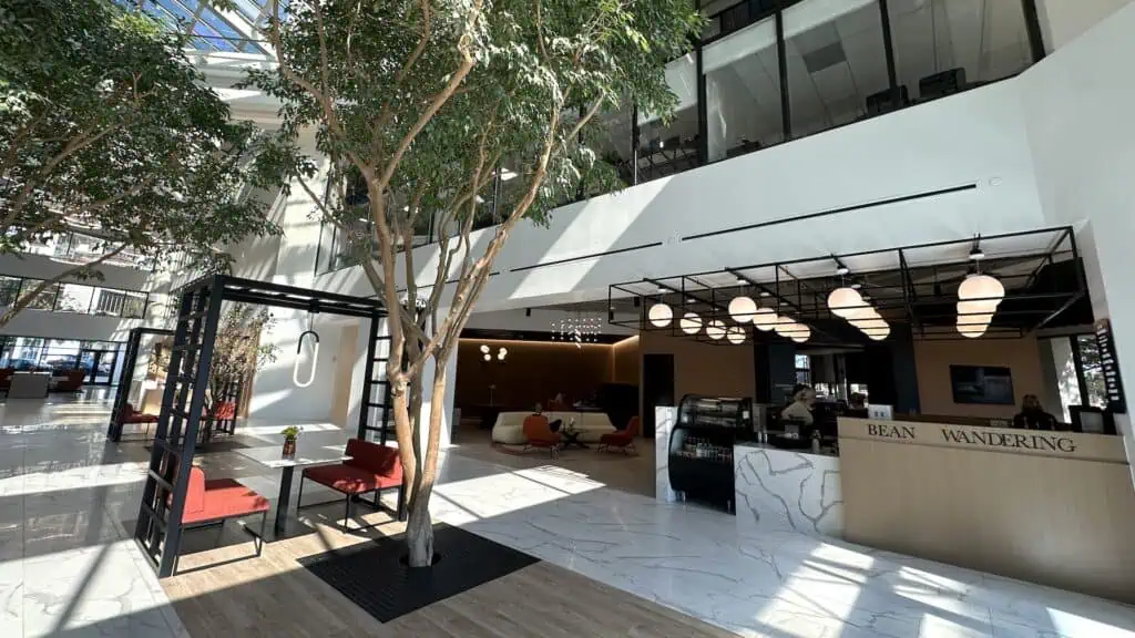 inside a large building with glass cielings and a tree growing through a planter in the tile floor