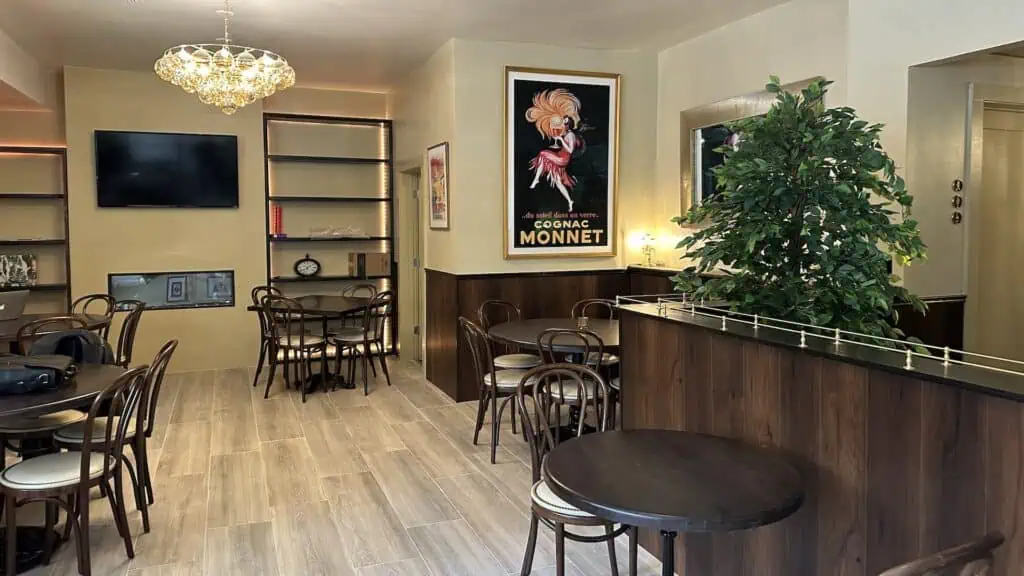 interior of a restaurant with small French-style tables arranged around a wooden handrail