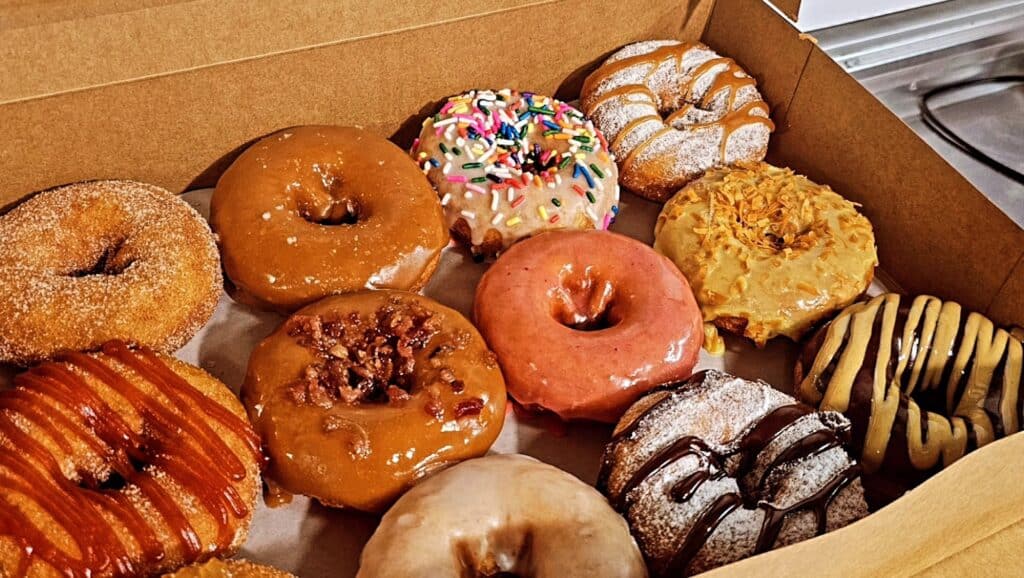 a box of donuts covered in different varieties of frostings 