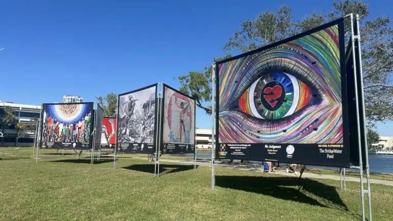 Three large displays feature 3 paintings each at a park. The most striking canvas features a large eye filled with all the colors of the rainbow