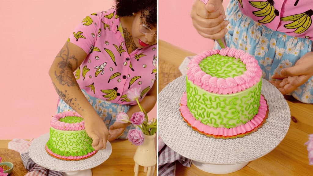 a baker decorates a bright green and pink cake. 