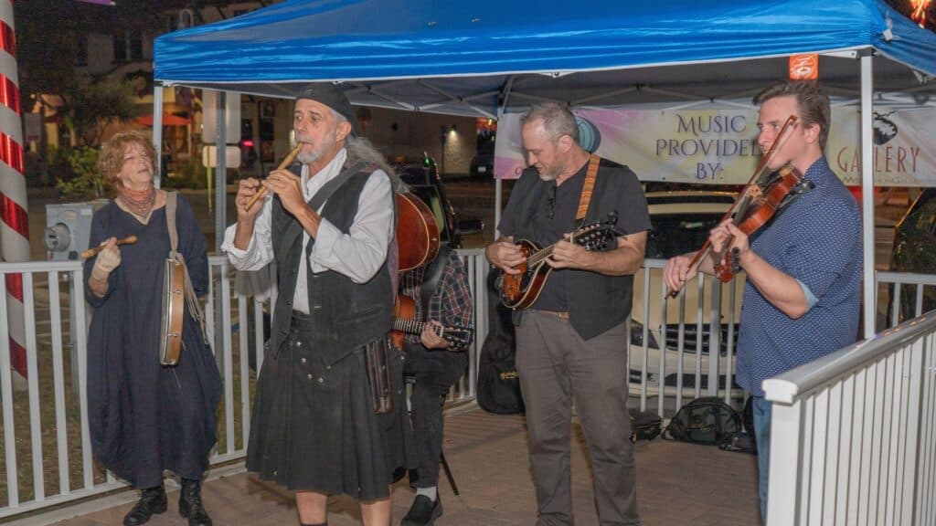 a band performing on the sidewalk during a vendor fair