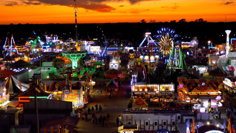 A large fair was photographed at sunset. big rides can be seen