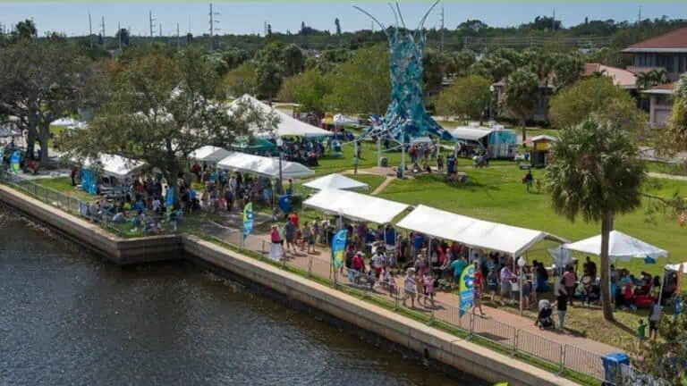 aerial view of a waterfront park during a festival with multiple vendor tents set up