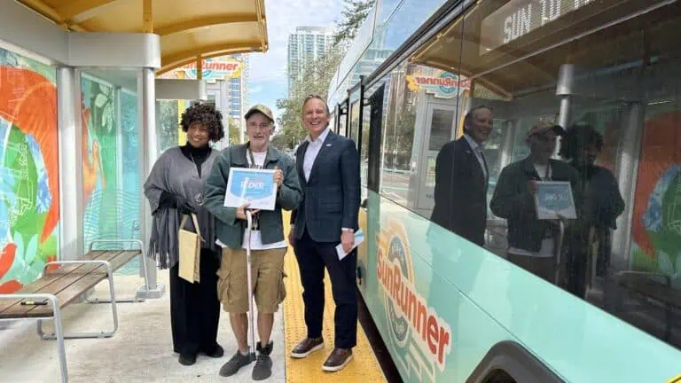 three people stand in front of a bright blue bus