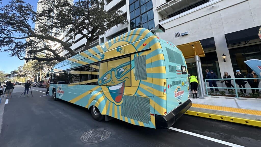 exterior of a blue bus with a large smiling sun on the side of it