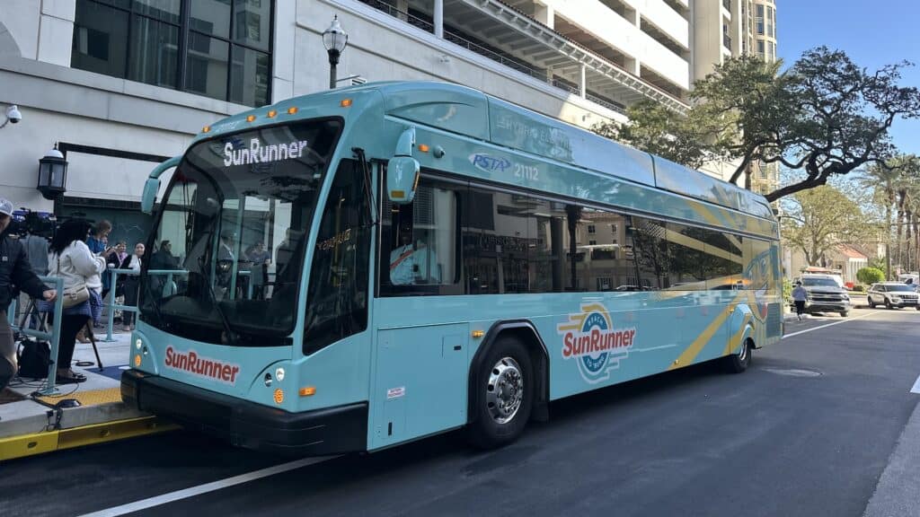 exterior of a blue bus pulled up at a station in a downtown area