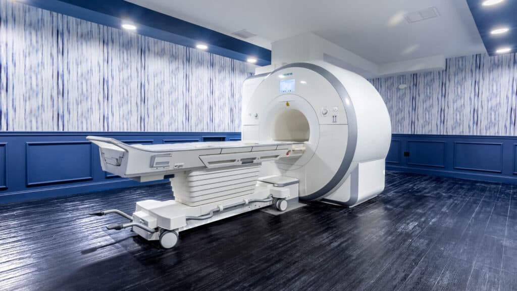 A clean and spacious room featuring a white MRI machine with blue accent walls.