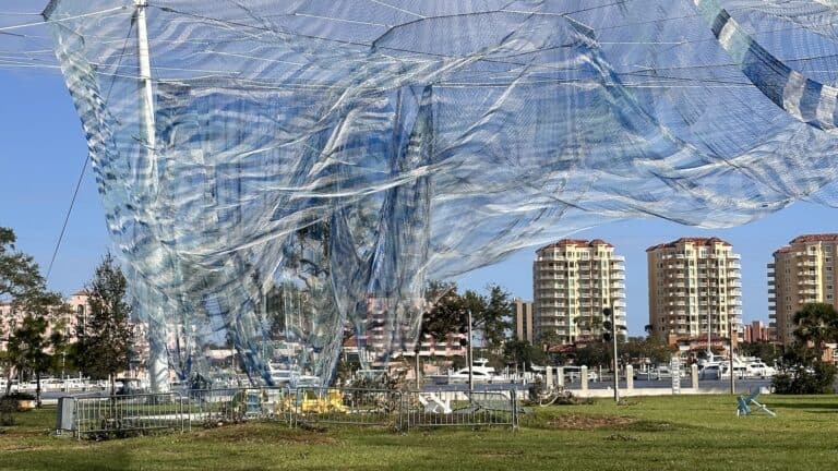 a large net sculpture on a waterfront area