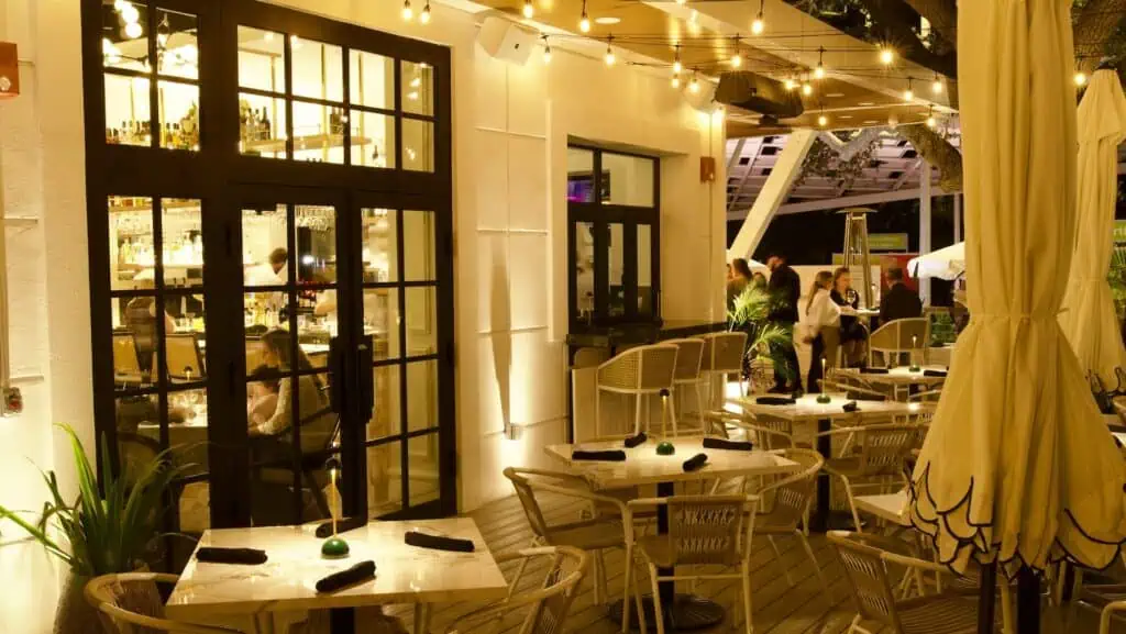 a patio dining area at night with multiple fire pits and heat lamps running