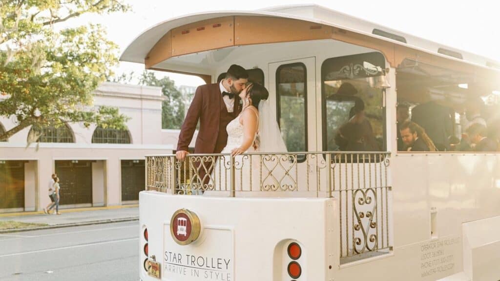 Two people embrace on in a wedding dress and tailored suit on a white and gold trolley