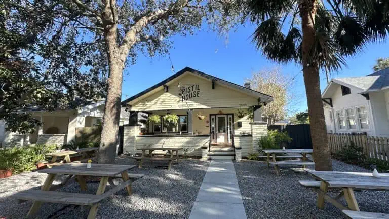 exterior of a cafe. It's a yellow house surrounded by trees with string lights hanging over picnic tables