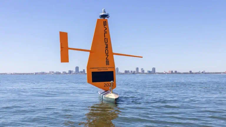 Orange sail on ocean with city skyline in background