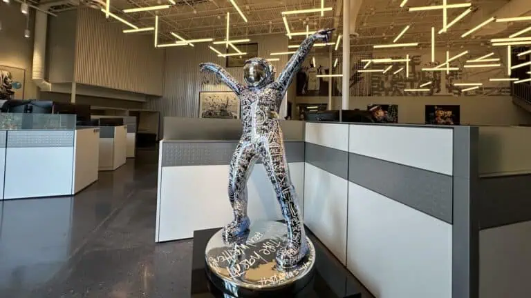 a tall astronaut sculpture inside of an office surrounded by tall cubicles
