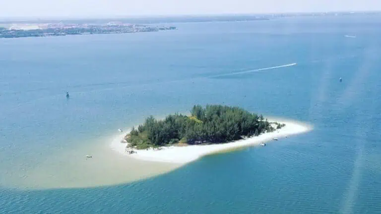 Aerial view of a small Pine Key island with white sand and lush greenery visible from above. YOu can see a sand bar stemming from the island