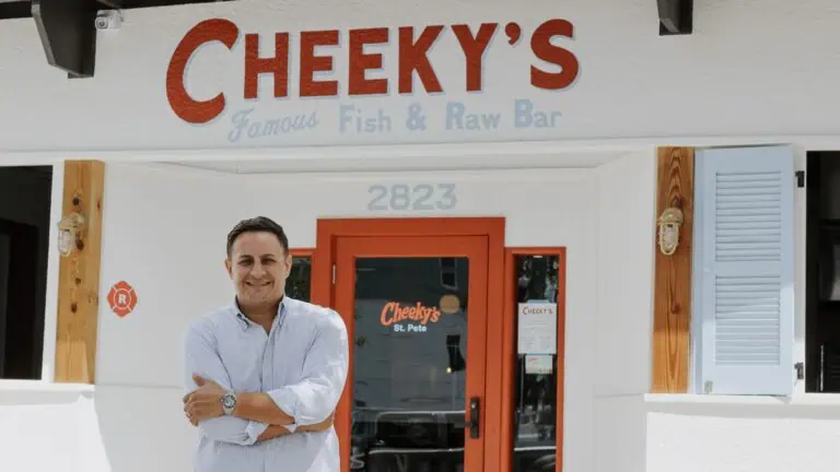 a head chef of a restaurant named Cheeky's poses in front of the restaurant