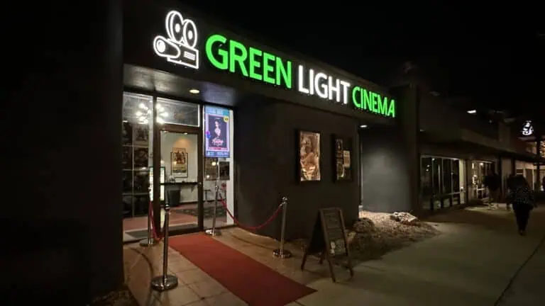 outside a local arthouse cinema with a green and white sign illuminated above the front door